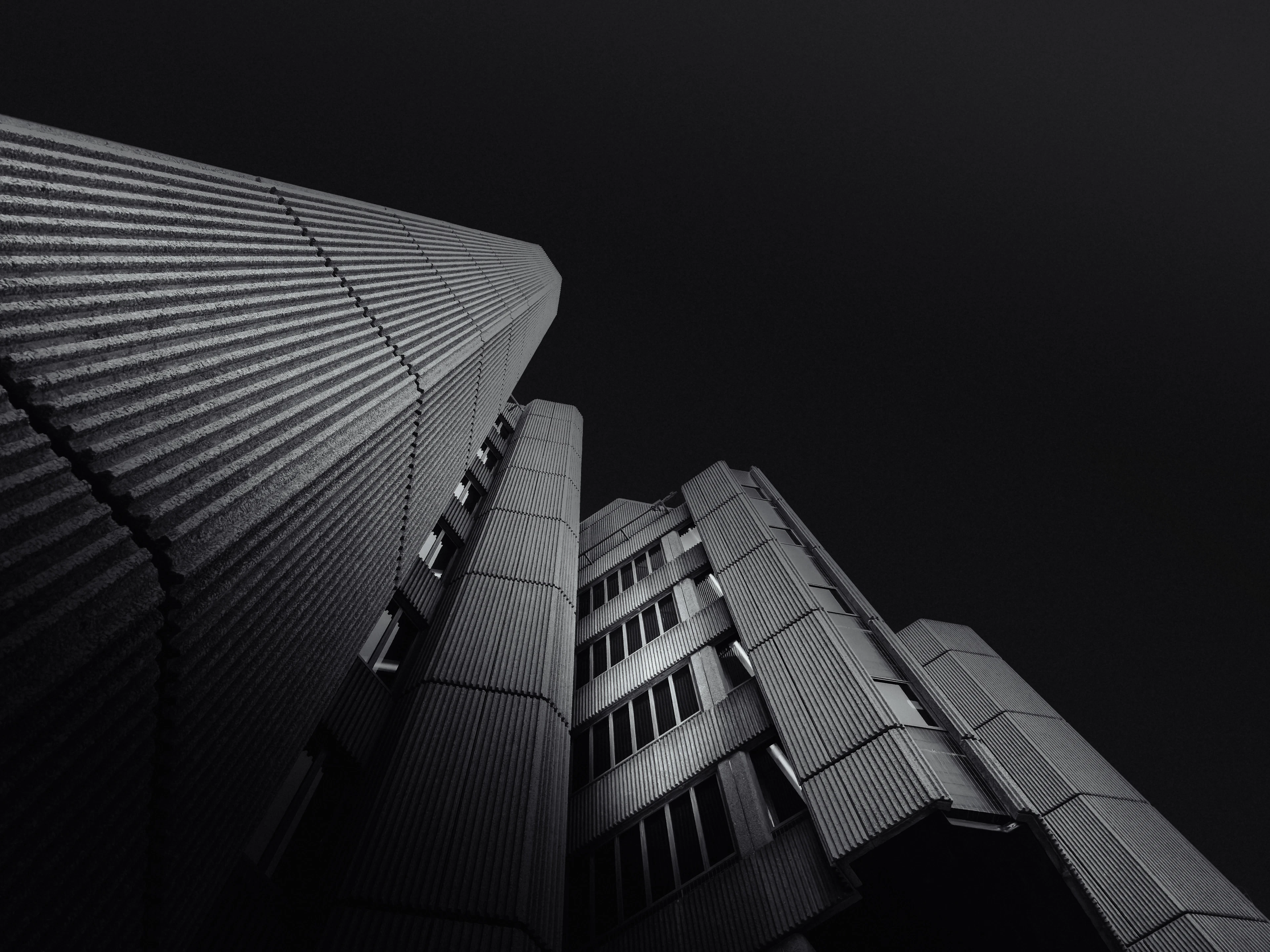 Black-and-white view up a ribbed concrete tower against a dark sky